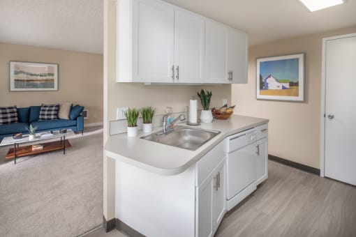 Kitchen with white cabinets and a sink and a living room with a couch at Summerfield, Tigard, OR