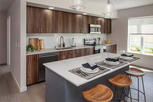 A modern kitchen with a large island and wooden stools.