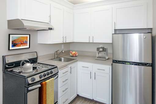 A kitchen with white cabinets and a stainless steel refrigerator.