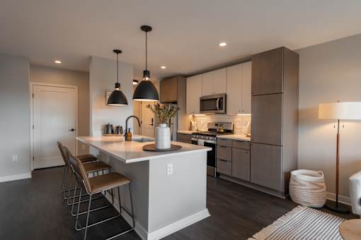 A modern kitchen with a white island and wooden chairs.