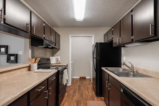 A kitchen with brown cabinets and a black refrigerator.