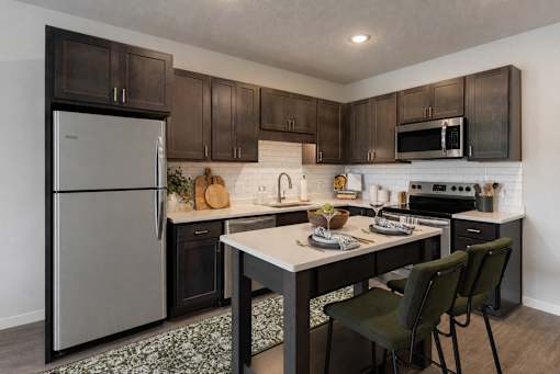 A kitchen with a refrigerator, oven, and sink.