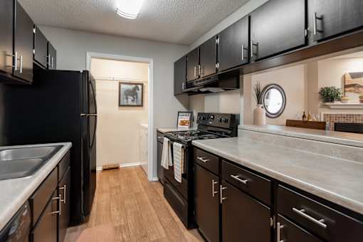 A kitchen with black cabinets and a black refrigerator.