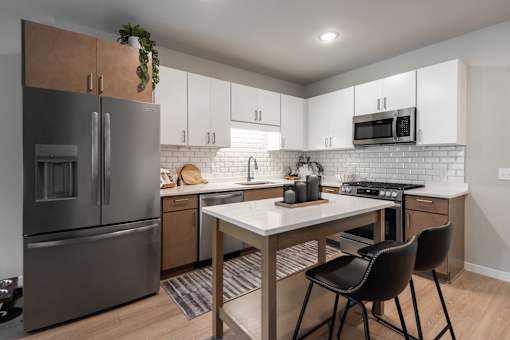 A modern kitchen with a white countertop and a black chair.