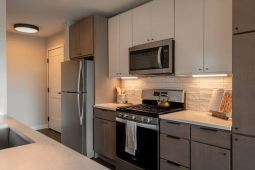 A modern kitchen with a stainless steel refrigerator, oven, and microwave.