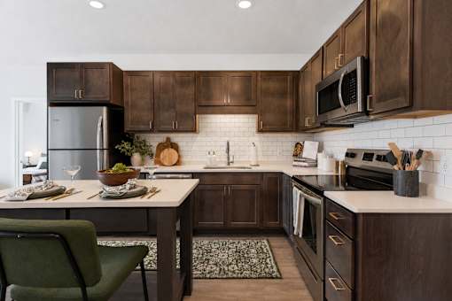 A modern kitchen with dark wood cabinets and a green chair.