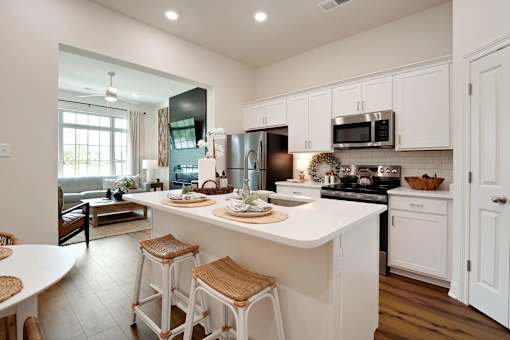 A kitchen with white cabinets and a large island with bar stools.