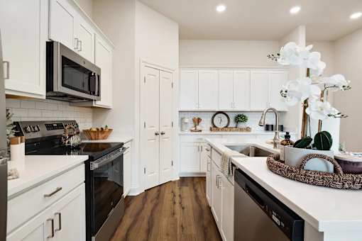 A kitchen with white cabinets and a black microwave.