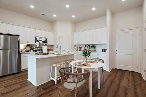 A kitchen with white cabinets and a wooden table.