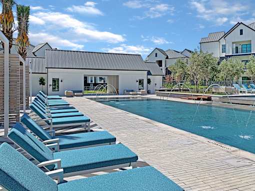 A pool with blue loungers in front of a house.