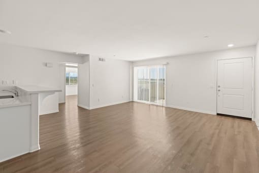 an empty living room with hardwood floors and white walls