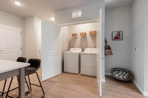 A laundry room with a washer and dryer, a table, chairs, and a basket.