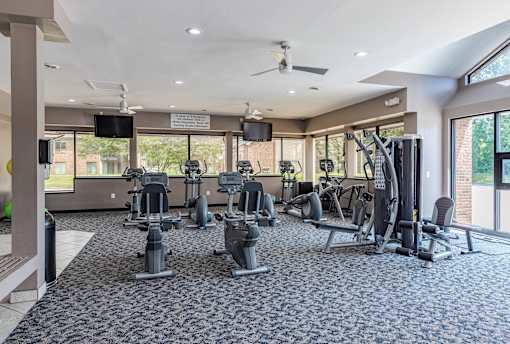 A gym with a variety of equipment including treadmills, stationary bikes, and weight machines.