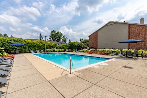 A pool surrounded by a patio and a building in the background.