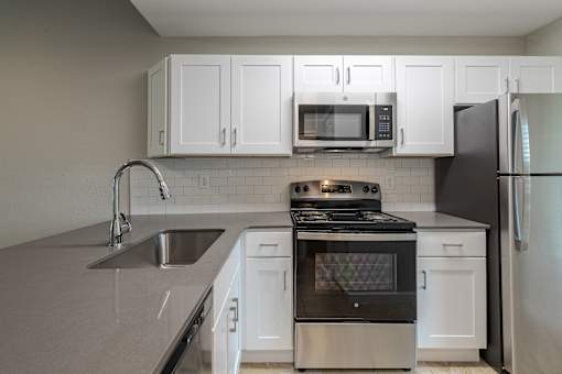 A modern kitchen with a stove, sink, and refrigerator.