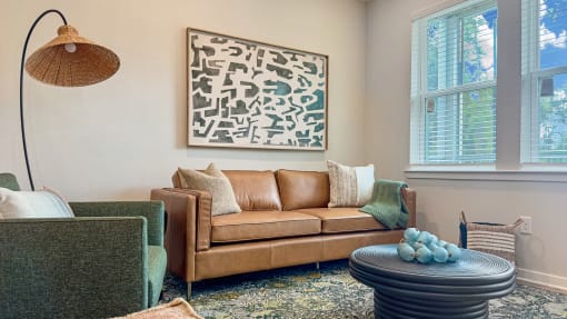 a living room with a couch and chairs and a painting on the wall