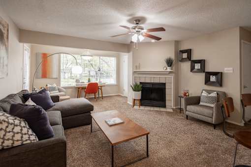 A living room with a grey couch, a brown coffee table, a fireplace, and a ceiling fan.