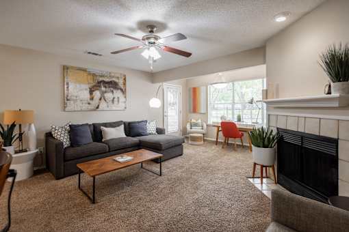 A living room with a grey couch, a coffee table, a fireplace, and a painting of a horse on the wall.