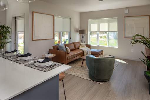 A modern living room with a brown leather couch and a grey armchair.