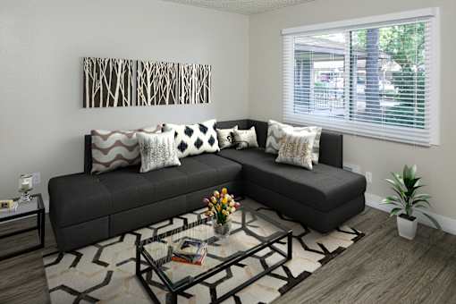 A black couch with pillows and a glass coffee table in front of it.