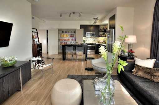A modern living room with a kitchen in the background.
