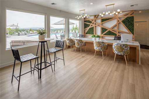A room with a long table and chairs with a green plant on the wall.