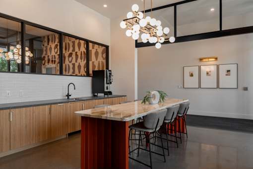 A modern kitchen with a wooden island and black chairs.