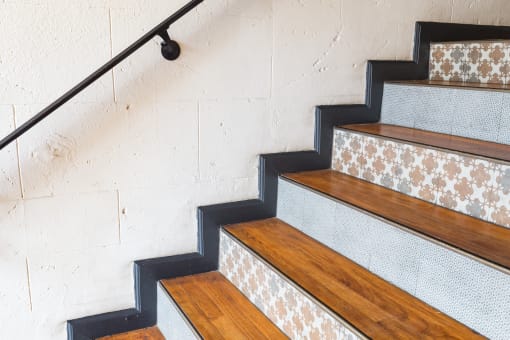 a staircase with wood treads and white tiles on the wall at Del Mor Apartments, Los Angeles, California