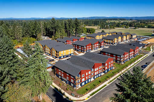 A large building complex with red and yellow buildings surrounded by trees.