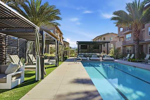 A pool surrounded by palm trees and lounge chairs.