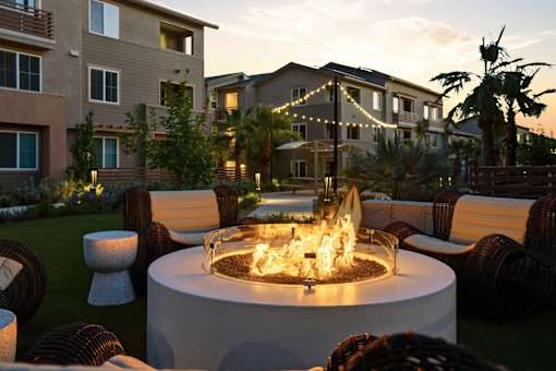 A fire pit in the middle of a patio surrounded by chairs.
