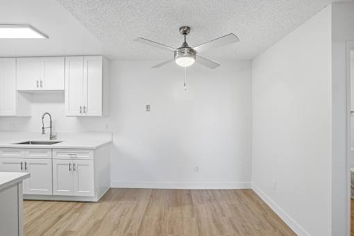 A kitchen with white cabinets and a wooden floor.