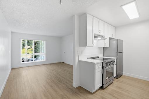 A kitchen with white appliances and wooden floors.
