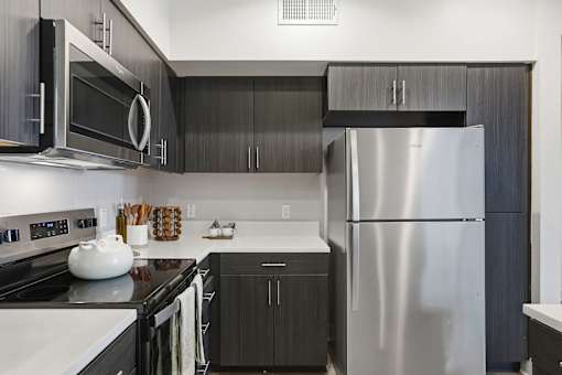 A modern kitchen with a stainless steel refrigerator, black cabinets, and a white stove top.