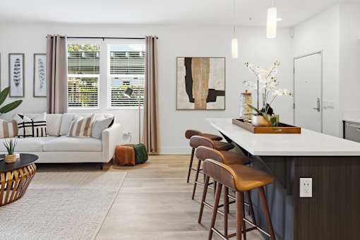 A modern kitchen with a bar stool and a white sofa.