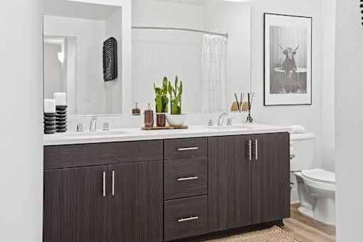 A bathroom with a white counter top and brown cabinets.
