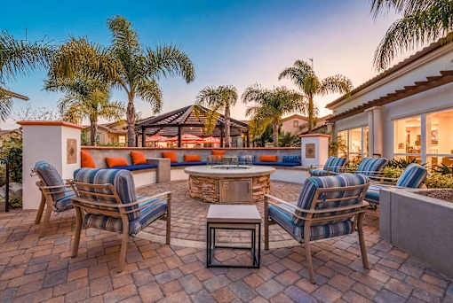 A patio with a table and chairs surrounded by palm trees.