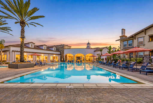A large swimming pool surrounded by lounge chairs and palm trees.