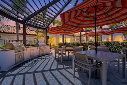 A patio with tables and chairs under striped umbrellas.