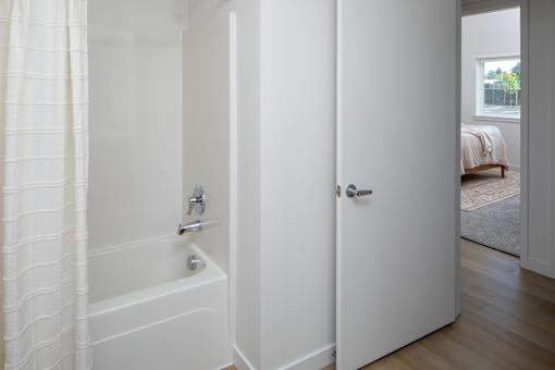 A white bathroom with a tub and a door.