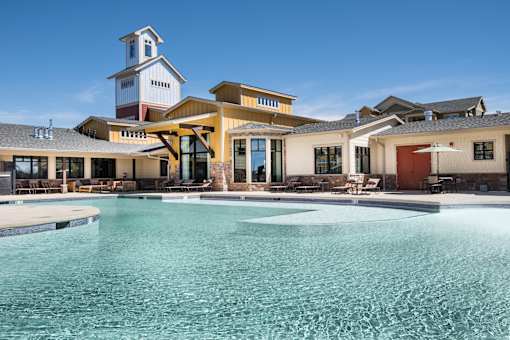 A large swimming pool in front of a building with a clock tower.