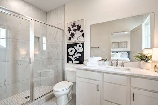 A white bathroom with a toilet, sink, and mirror.