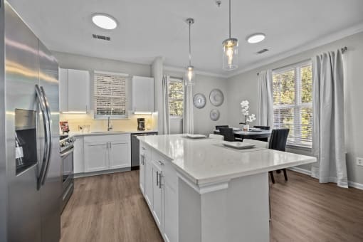 a white kitchen with a large island and stainless steel appliances