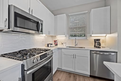 a kitchen with white cabinets and stainless steel appliances