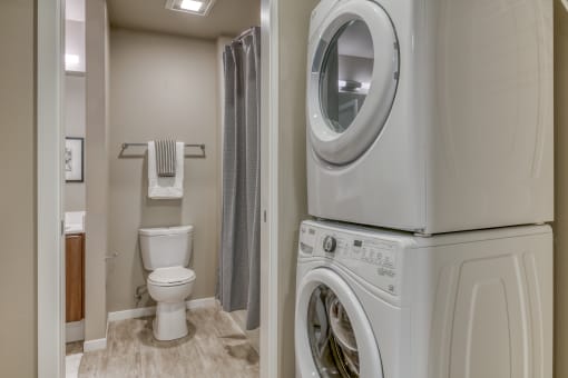 a washer and dryer in a bathroom with a toilet and a shower