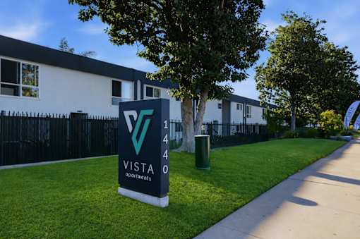 A sign for Vista Apartments stands in front of a building.