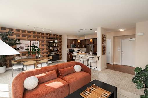 A living room with a couch, a coffee table, and a kitchen area in the background.