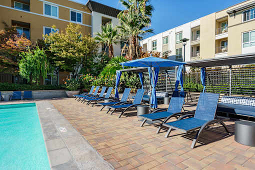 A pool area with blue chairs and a canopy.