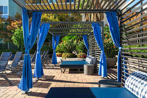A patio with blue umbrellas and a bench.