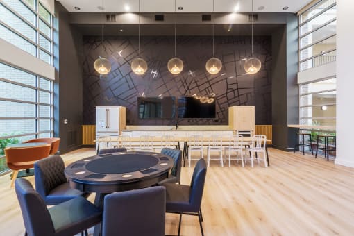 a large room with a round table and chairs and a bar in the background